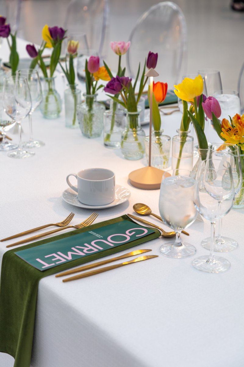 A decorative table setting with a green menu stating "Gourmet" 