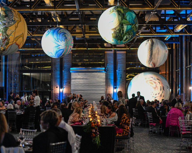 A large gala in a dimly lit space with decorative spheres hanging from the ceiling